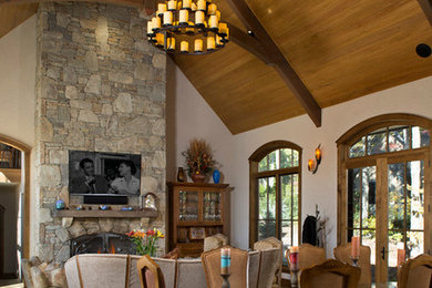 Foto de salón abierto rústico grande con paredes beige, suelo de madera en tonos medios, todas las chimeneas, marco de chimenea de piedra, televisor colgado en la pared y suelo marrón