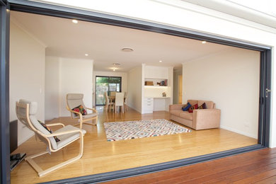 Example of a mid-sized minimalist open concept light wood floor living room design in Brisbane with white walls