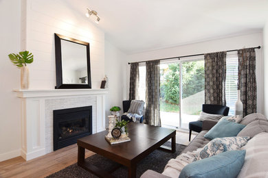 バンクーバーにある低価格の中くらいなトラディショナルスタイルのおしゃれなLDK (白い壁、クッションフロア、標準型暖炉、タイルの暖炉まわり、壁掛け型テレビ、茶色い床) の写真