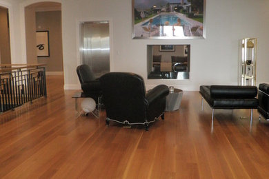 На фото: двухуровневая гостиная комната среднего размера в стиле фьюжн с светлым паркетным полом, серыми стенами и телевизором на стене