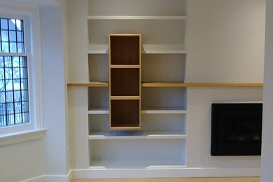 Foto de biblioteca en casa minimalista de tamaño medio sin televisor con paredes blancas, suelo de madera clara, todas las chimeneas y suelo amarillo