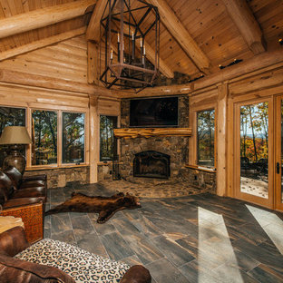 Cette image montre un salon chalet de taille moyenne et fermé avec une salle de réception, un mur beige, un sol en carrelage de porcelaine, une cheminée double-face, un manteau de cheminée en pierre, un téléviseur fixé au mur et un sol gris.