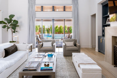 Esempio di un ampio soggiorno chic con pareti bianche, parquet chiaro, TV a parete e pavimento beige