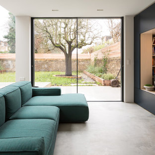 Contemporary formal open plan living room in London with white walls, concrete flooring, a built-in media unit and grey floors.