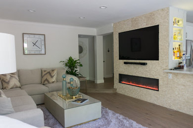 Imagen de salón con barra de bar clásico renovado pequeño con suelo laminado, marco de chimenea de piedra, pared multimedia y suelo marrón