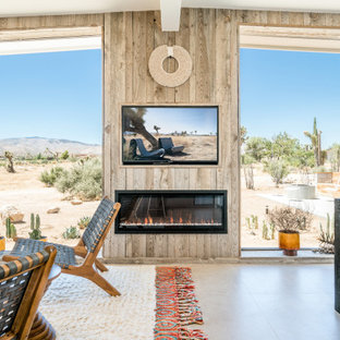 Foto de salón para visitas abierto, actual, de tamaño medio, con chimenea lineal, marco de chimenea de madera, paredes beige, suelo de cemento, pared multimedia y suelo marrón