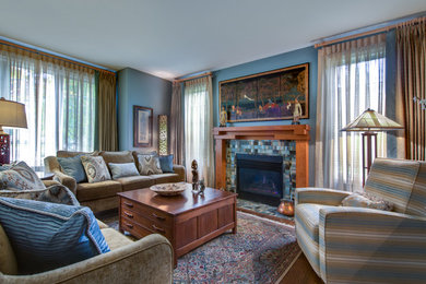 Ejemplo de salón para visitas cerrado clásico renovado de tamaño medio con paredes azules, suelo de madera en tonos medios, todas las chimeneas y marco de chimenea de baldosas y/o azulejos