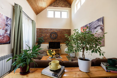 Ejemplo de salón tipo loft pequeño sin chimenea con paredes amarillas, suelo de madera clara, televisor independiente, madera y ladrillo