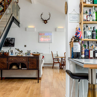 This is an example of a medium sized eclectic open plan living room in Hampshire with white walls, light hardwood flooring, a wall mounted tv, beige floors and a home bar.