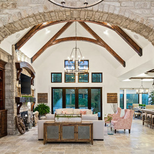 Idee per un ampio soggiorno country aperto con sala formale, pareti multicolore, pavimento in travertino, camino classico, cornice del camino in pietra, TV a parete e pavimento multicolore