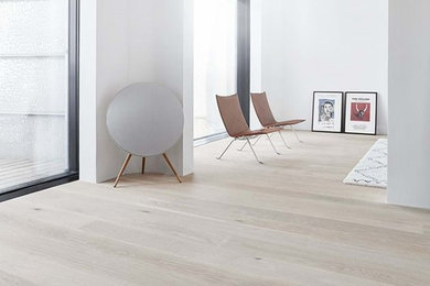 This is an example of a large scandi open plan living room in Copenhagen with white walls, light hardwood flooring and white floors.