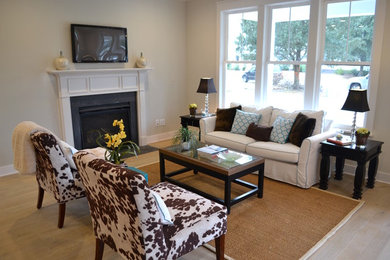 Example of a classic light wood floor living room design in Charleston with beige walls, a standard fireplace and a wall-mounted tv