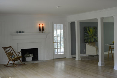 Example of a mid-sized beach style open concept light wood floor and beige floor living room design in New York with white walls, a standard fireplace, a wood fireplace surround and no tv