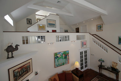 Bild på ett mellanstort funkis loftrum, med vita väggar och mellanmörkt trägolv