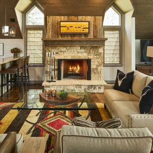 Inspiration for a mid-sized southwestern open concept dark wood floor living room remodel in Other with beige walls, a standard fireplace, a stone fireplace and a wall-mounted tv