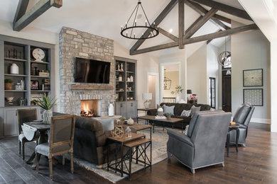 Inspiration for a huge timeless open concept dark wood floor and brown floor living room remodel in St Louis with beige walls, a standard fireplace, a stone fireplace and a wall-mounted tv
