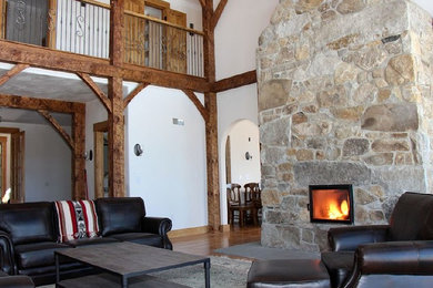 Aménagement d'un grand salon montagne ouvert avec une salle de réception, un mur blanc, un sol en bois brun, une cheminée standard, un manteau de cheminée en pierre et un sol marron.
