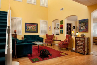 Diseño de salón abierto ecléctico de tamaño medio sin chimenea con paredes amarillas y suelo de madera clara