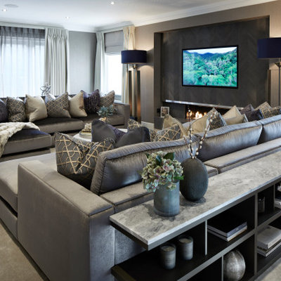 Large trendy enclosed carpeted and gray floor living room photo in Surrey with gray walls, a hanging fireplace, a wood fireplace surround and a wall-mounted tv