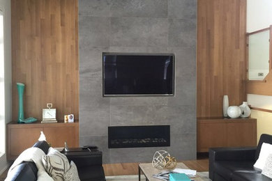 Diseño de salón abierto minimalista grande con suelo de madera clara, marco de chimenea de piedra y pared multimedia