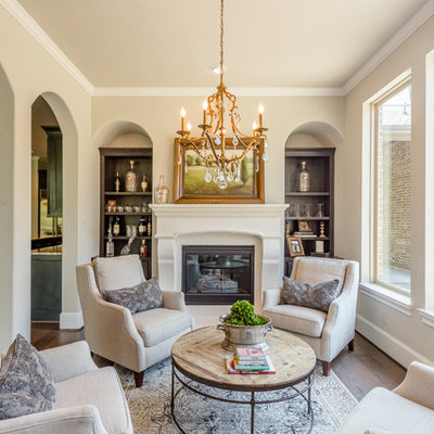 Elegant medium tone wood floor and brown floor living room photo in Houston with beige walls and a standard fireplace