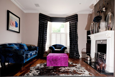 ロンドンにある高級な広いコンテンポラリースタイルのおしゃれな応接間 (ベージュの壁、濃色無垢フローリング、標準型暖炉、漆喰の暖炉まわり、茶色い床、青いソファ) の写真