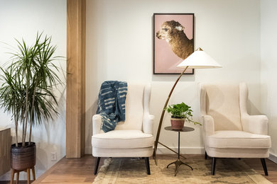 Diseño de salón abierto minimalista pequeño con paredes blancas, suelo de madera en tonos medios y televisor colgado en la pared