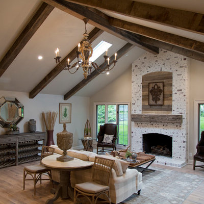 Inspiration for a large country formal and open concept medium tone wood floor and brown floor living room remodel in Kansas City with gray walls, a standard fireplace and a stone fireplace