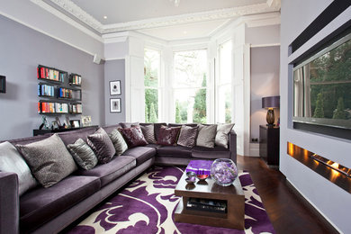 Großes, Abgetrenntes Modernes Wohnzimmer mit grauer Wandfarbe, dunklem Holzboden, Gaskamin, verputzter Kaminumrandung und Multimediawand in Berkshire