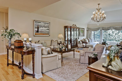 Modelo de salón abierto clásico grande con paredes beige y suelo de madera clara