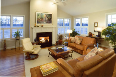 Cette photo montre un salon chic de taille moyenne et fermé avec un mur beige, parquet clair, une cheminée standard, un manteau de cheminée en plâtre et aucun téléviseur.