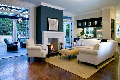 ロサンゼルスにあるお手頃価格の中くらいなコンテンポラリースタイルのおしゃれなリビング (ベージュの壁、濃色無垢フローリング、標準型暖炉、漆喰の暖炉まわり、茶色い床) の写真