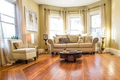 Example of a mid-sized transitional enclosed medium tone wood floor and brown floor living room design in Boston with beige walls, a standard fireplace and a wood fireplace surround