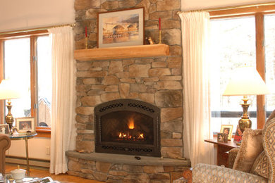 This is an example of a rustic living room in Boston with white walls, light hardwood flooring, a standard fireplace and a stone fireplace surround.