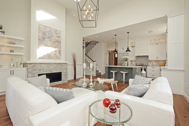 Example of a mid-sized transitional open concept medium tone wood floor living room design in Vancouver with beige walls, a standard fireplace, a stone fireplace and a media wall