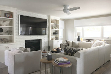 Example of a large transitional open concept laminate floor and gray floor living room design in Denver with gray walls, a standard fireplace, a brick fireplace and a wall-mounted tv
