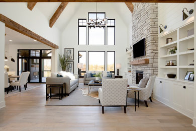 Huge transitional open concept light wood floor, beige floor, vaulted ceiling and shiplap wall living room photo in Minneapolis with white walls, a standard fireplace, a stone fireplace and a media wall