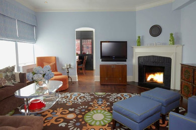 Inspiration for a mid-sized transitional enclosed medium tone wood floor living room remodel in New York with blue walls, a corner fireplace, a wood fireplace surround and a wall-mounted tv