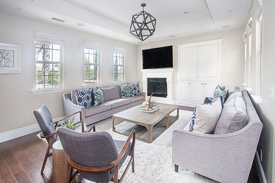 Example of a large transitional formal and open concept dark wood floor living room design in Orange County with gray walls, a standard fireplace, a plaster fireplace and a wall-mounted tv