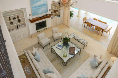 Cette image montre un grand salon traditionnel ouvert avec un mur beige, un sol en travertin, une cheminée standard et un sol beige.