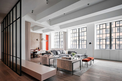 Example of an urban medium tone wood floor and brown floor living room design in New York with white walls