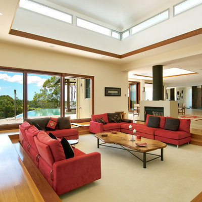 Example of a mid-sized minimalist open concept medium tone wood floor living room design in Brisbane with beige walls and a standard fireplace