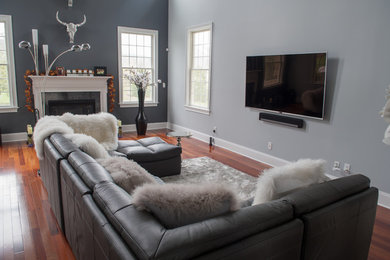 フィラデルフィアにある高級なコンテンポラリースタイルのおしゃれなLDK (グレーの壁、濃色無垢フローリング、標準型暖炉、木材の暖炉まわり、壁掛け型テレビ、茶色い床) の写真