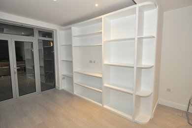 Photo of a large contemporary open plan living room in London with white walls, laminate floors and a built-in media unit.