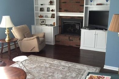 Mid-sized elegant open concept dark wood floor living room photo in Cleveland with blue walls, a standard fireplace, a brick fireplace and a tv stand