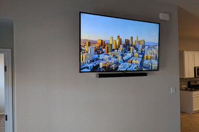 オースティンにある低価格のおしゃれなリビング (ベージュの壁、カーペット敷き、壁掛け型テレビ) の写真