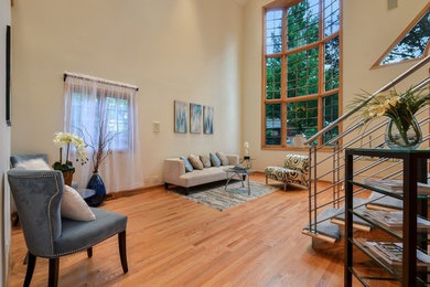This is an example of a medium sized modern mezzanine living room in Chicago with white walls, medium hardwood flooring and brown floors.