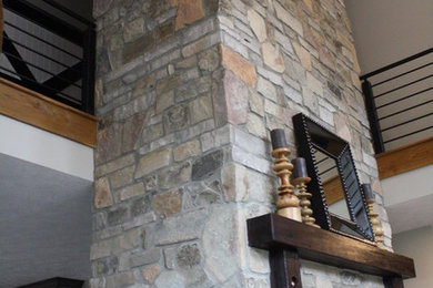 Diseño de salón campestre con paredes grises y marco de chimenea de piedra