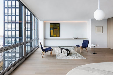 Modelo de salón abierto moderno pequeño sin chimenea y televisor con paredes blancas y suelo de madera clara