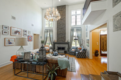 Example of a large transitional open concept bamboo floor living room design in New Orleans with white walls, a standard fireplace, a stone fireplace and no tv